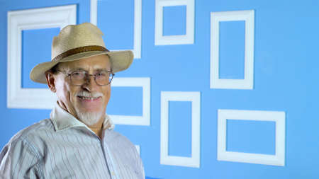 studio portrait of an old man looking at camera on a colorful wallの写真素材