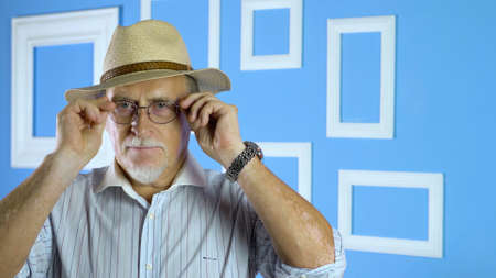 studio portrait of an old man looking at camera on a colorful wallの写真素材