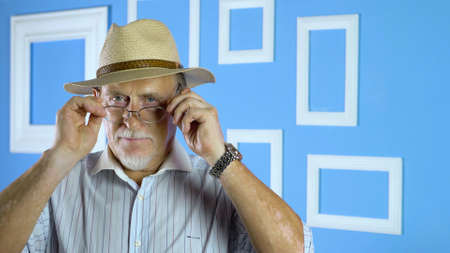 studio portrait of an old man looking at camera on a colorful wallの写真素材