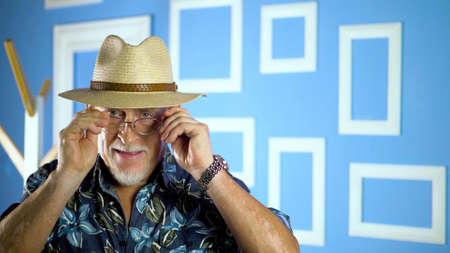 studio portrait of an old man looking at camera on a colorful wallの写真素材