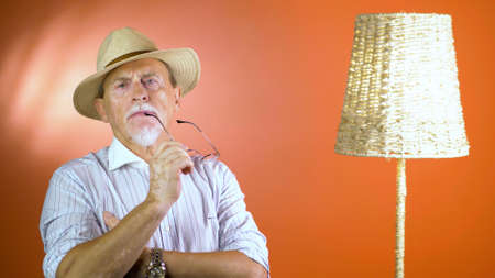 Caucasian senior man's portrait at home on orange studio background. Old male emotional model. Concept of human emotions, facial expression. Copyspace.の写真素材
