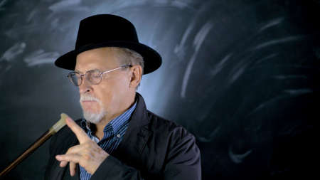 Close up portrait of an attractive luxurious gentleman with a hat over gray background. Retro styled male portraitの写真素材
