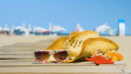 Beautiful summer holiday beach background with straw hat and seashells. Summer concept with accessories on the sandy beachの写真素材