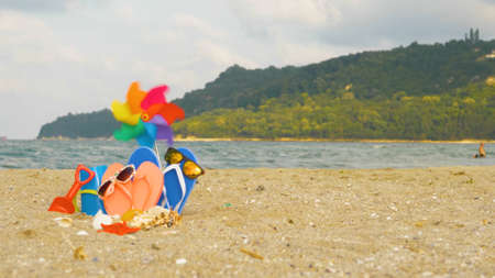Flip flops, sunglasses and seashells on beach sand. Summer holiday background, vacation and travel items.の写真素材