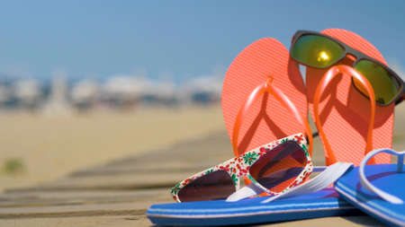 Starfish, seashells and flip-flops on wooden board. Summer holiday background, vacation and travel items. Summer concept with accessories on the sandy beachの写真素材