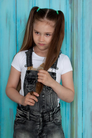 Russia, Izhevsk - May 23, 2017: Serious little girl is standing near the blue door. Carefree childhood.のeditorial素材