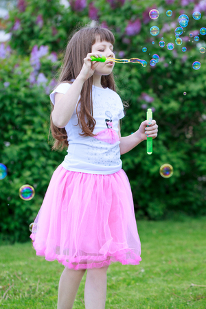 Beautiful little girl is playing with soap bubbles. Carefree childhood.の写真素材