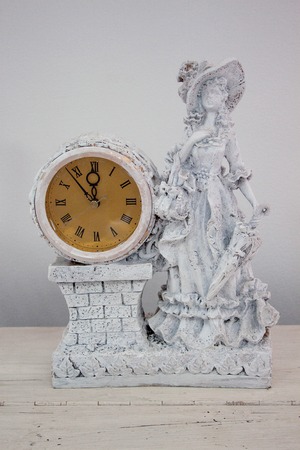Clock with a woman statue is standing on a wooden table. Beautiful interior.の写真素材