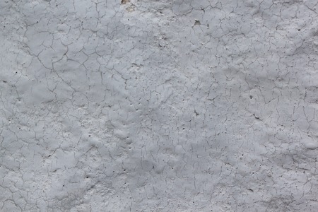 Pieces of gray paint on a rough painted wall. Used as a background. Copy space for your text.