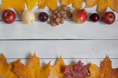 Dry leaves and various fruits are lying on a wooden desk. Autumn still life. Copy space for your...
