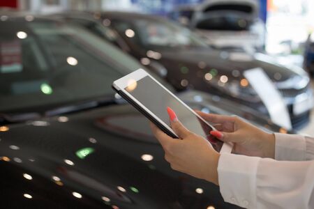 Woman dealer using digital tablet at dealer showroom. Touching screen digital tablet. Modern working...