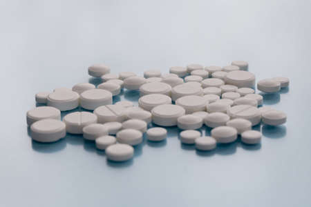 Pile of white pills isolated on blue
