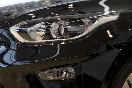 New modern unknown car with elegant head lamps. Cropped image. Close up. Modern transportation.