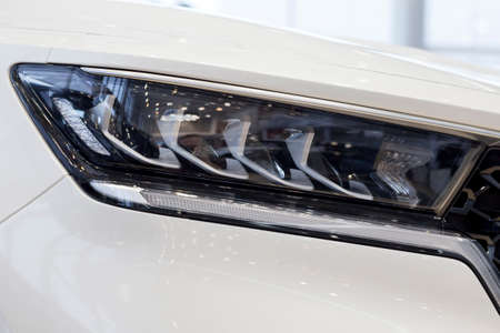 New modern unknown car with elegant head lamps. Cropped image. Close up. Modern transportation.