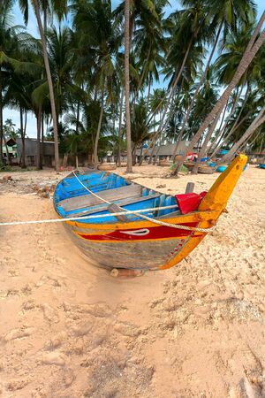 The old boat on sand under green palm treesの写真素材