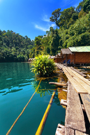 Houses on stilts stand on clear lake among the green trees.の写真素材