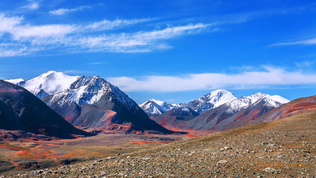 The mountainous landscape. The chain of mountain peaks covered with white snow. At the foot of the barren stone desert. (Mountain Altai)の写真素材