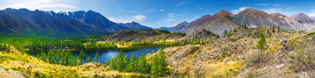Panorama of a mountain landscape. Clear lake mirror water. Coniferous forest on rocky hills. Altai,...