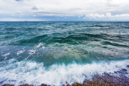 Sea wave during high tide at the shore. The sea horizon and the gloomy rainy sky.の写真素材