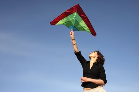 woman the brunette starts the kite, on a background of the blue skyの写真素材