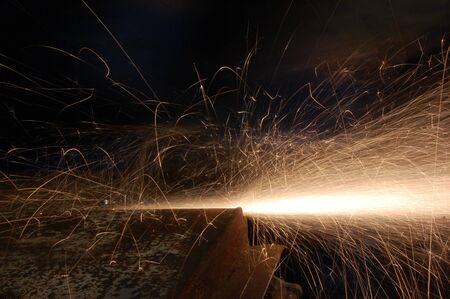 Shower of orange sparks from a worker grinding steel 