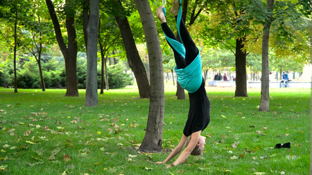 A young girl in a park engaged in aerial yoga. This type of yoga on special fabric canvasesの写真素材