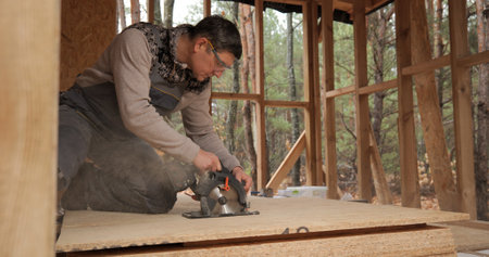 A worker uses a circular saw to cut plywood. Construction of a new wooden house using frame technology. The concept of building wooden houses.の写真素材