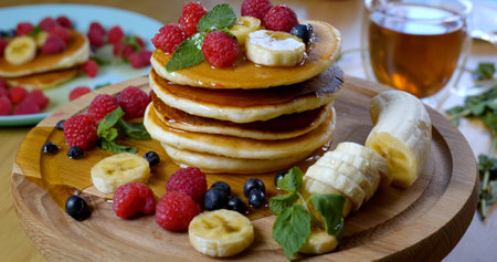 Delicious breakfast. Pancakes with raspberry, banana and a mint leaf and honeyの写真素材