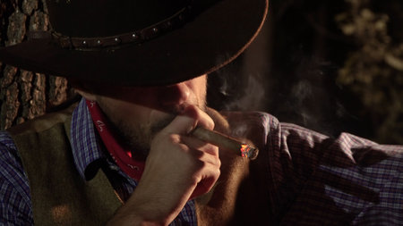 Cowboy with a cigar in the forest at night. Life in the wild west of Americaの写真素材