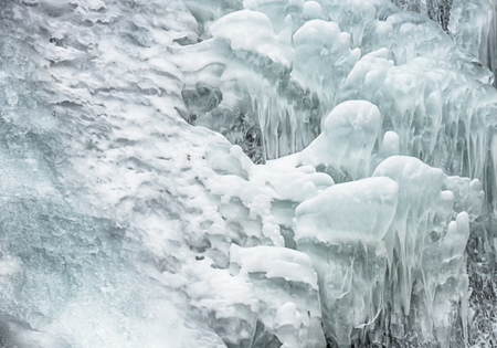Close up view of a frozen waterfall in the river. Fresh ice in mountains. Background or texture for...