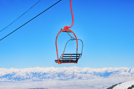 Orange chairlift  surrounded by an amazing winter landscape with blue sky  and mountains.の写真素材
