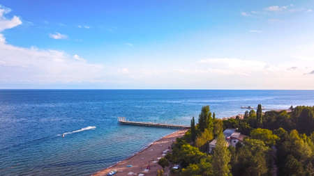 Idyllic summer landscape with lake near mountain with reflection from clouds and forest. Issyk kul,...