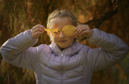 Happy girl laughing and playing in autumn leavesの写真素材