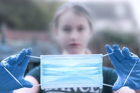 Caucasian Girl wearing protection face mask and blue nitrile surgical gloves against coronavirus....