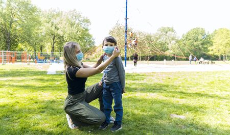 Mother with son at the playground  in face masks. People wears a protective medical masks during an...