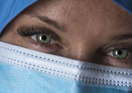 Tired doctor in mask looks at camera. Close up. Selective focusの写真素材