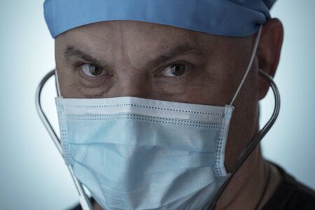 Portrait of tired doctor. Doctor wearing medical mask looking into camera. COVID-19. Coronavirus pandemicの写真素材