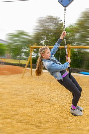 The girl climbing and sliding on slide in the playground. Happy children playing and having fun at...