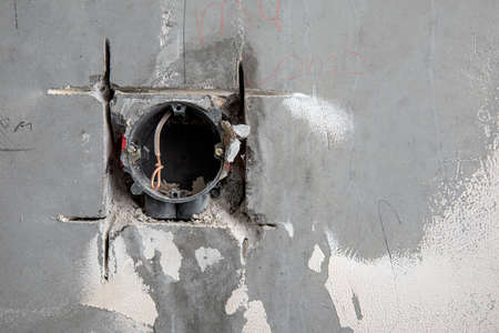 Hidden installation of electrical wires in a old plastering wall. Repair in an old apartment and transfer of socketsの写真素材
