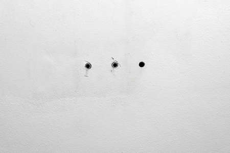 Industrial background. Renovation and restoration. Hole and dowels in an old dirty white wall. Dowel pin inside old peeled wall for different editing projectsの写真素材