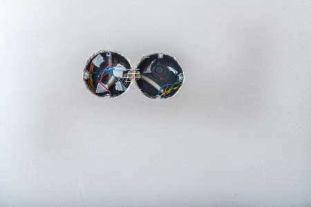 Opened junction box and electrical wire on the old white wall. Electrical works on construction siteの写真素材