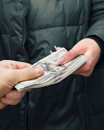 Male hand giving female a wad of hundred dollar bills. Closw upの写真素材