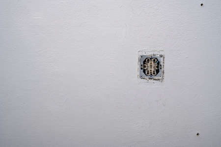 Opened old socket an old dirty white wall. Repair in an old apartment and transfer of sockets.