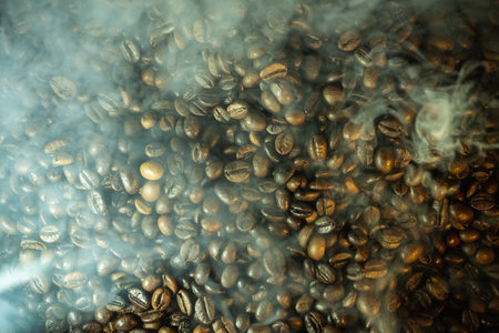 Close-up of roasted coffee beans with soft steam and haze, dramatic warm lighting, rich texture...