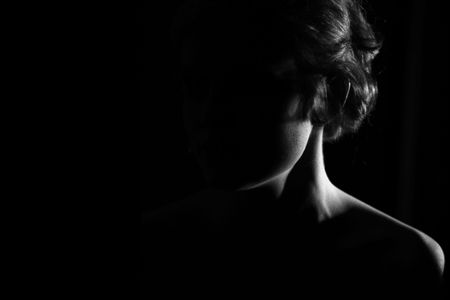 neck of young girl on black background with soft lightの写真素材