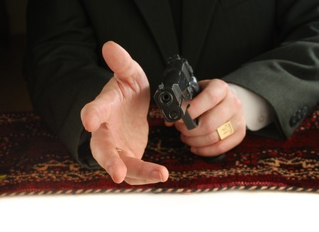 hands of man on an east carpet with a pistol