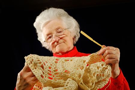 portrait of elderly woman is in red with  hook knitting (wool)の写真素材