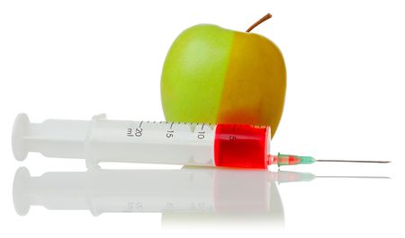 green apple and a syringe with red fluidの写真素材