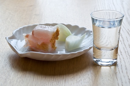 glass with a clear liquid and a small dish of bacon and onionsの写真素材