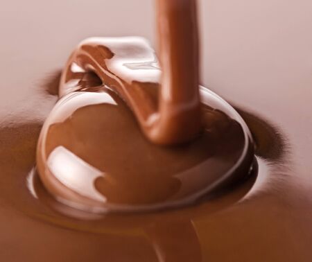 Melted chocolate being poured. Chocolate is falling in a ribbon from above and is shiny and reflectiveの写真素材